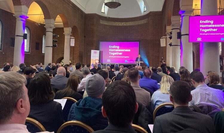 The back of the audience of organisations watching a presentation screen from Homeless Link with banners showing Homeless Link's manifesto 'A Home for Everyone'