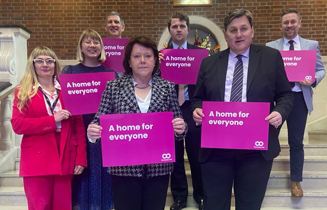 Lobby day - morning meeting cropped Representatives from Two Saints, MPs and one representative from Homeless Link standing on steps and holding up signs from Homeless Link's manifesto title 'A Home for Everyone'